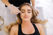 Brow master in transparent glowes gives shape to pull out with forceps previously painted with henna eyebrows in a beauty salon. Beautiful blond hair model. Top view