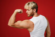 © ViDi Studio - Side back view young strong sporty toned sportsman man 20s wear white clothes spend time in home gym show biceps muscle on hand power isolated on plain red background Workout sport fit body concept