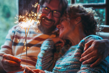 Wall Mural - Romantic couple in love at home celebrate together with sparkler light in the night hugging and smiling each other. New year and anniversary event concept. Man and woman enjoy relationship celebrating