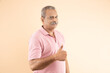 © GAJENDRRA BHATI  - Portrait of happy indian senior man doing thumbs up over beige studio background, all good, okay gesture. Retired asian old male.