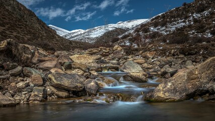 Sticker - Beautiful shot of rocky stream in middle of snow covered valley at foot of Dongda Mountains, Tibet