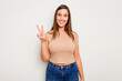 © Asier - Young caucasian cute woman isolated on white background showing victory sign and smiling broadly.