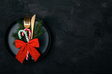 Christmas Table Setting With Black Empty Plate And Golden Cutlery, Dark Background, Top View With Copy Space