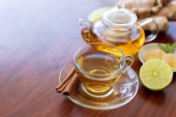 Wall Mural - a cup of tea with ginger root, lime, cinnamon and teapot on white background. Health drink concept.