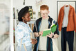 Waist up portrait of two young people looking at used books in thrifting shop or swap event