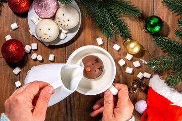 Wall Mural - Making winter hot drink, preparation funny Christmas characters with hot chocolate bomb. Homemade hot chocolate cocoa balls made with Christmas snowman, reindeer, snowflake decor