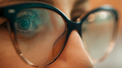 Businesswoman working at night looking at monitor, reflections in eyeglasses. The programmer works at the computer over the program in a dark room.