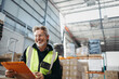 © Jacob Lund - Senior warehouse supervisor smiling happily while holding a clipboard