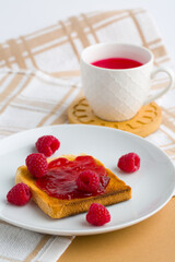 Wall Mural - Cup of red tea and toasted bread with raspberry jam