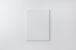 Blank vertical art canvas on wall. Clean surface for mockup, art presentation. Soft light on white wall