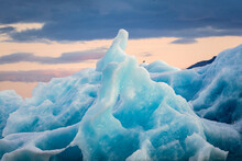 Flock Of Bird Perched On Blue Iceberg Floating On Glacial Lagoon In The Evening At Jokulsarlon