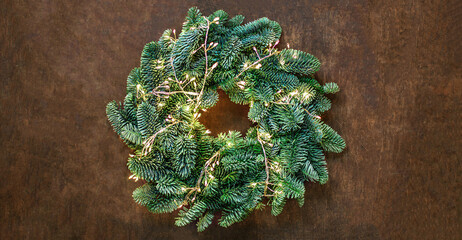 Wall Mural - christmas wreath with golden lights garland on dark wooden background top view, copyspace. xmas, nat