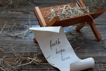 Manger of Jesus and papyrus with words faith hope love, christmas nativity scene concept