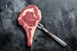 Raw cowboy steak, rib eye steak with bone, beef marbled meat on butcher cutting board. Black background. Top view. Copy space