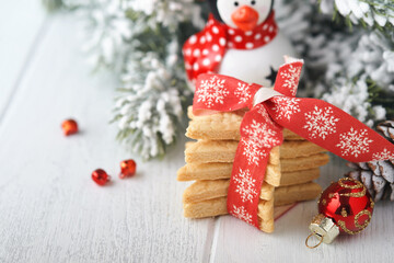 Wall Mural - Christmas shortbread cookies or gingerbread stars with red ribbon, festive decoration, fir tree,balls and light garland. Traditional german cookies. Christmas celebration traditions family culinary.