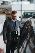 © Serhii - Visiting car dealership. Handsome bearded man is stroking his new car and smiling
