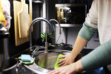A Woman Washes Dirty Dishes In The Kitchen Sink