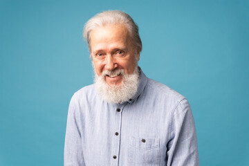 Retired old man with white hair and beard open mouth shiny smile haiving fun excited over blue color background and copy space