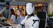 © ihorvsn - Digital transformation. Robot looking at camera in office. White device turning head and looking straight. Humanoid working at computer. Support worker. Artificial intelligence. Communication network.