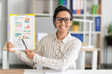 Poster - Online meeting concept. Happy female manager having video call, showing diagrams to camera, sitting in office