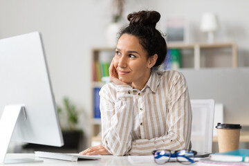 Poster - Dreamy young businesswoman thinking of new business strategy, sitting at workplace in office, looking aside and smiling