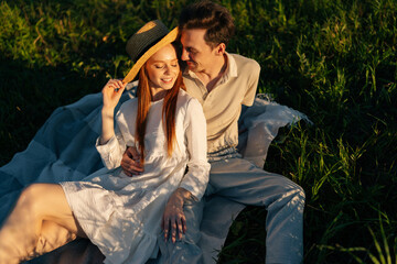 Wall Mural - romantic smiling young couple in love with closed eyes sitting hugging together on beautiful green m