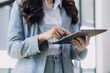 © ARMMY PICCA - Woman hand using smart phone and laptop in outdoor nature park and sunset sky with bokeh light abstract background. Technology business and freelance working concept. Vintage tone filter color style.
