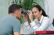 female optometrist examines eyes of male patient