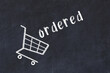 Chalk drawing of shopping cart and word ordered on black chalboard. Concept of globalization and mass consuming