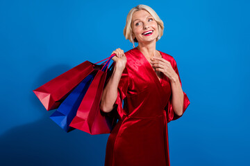 Canvas Print - Photo of cute dreamy retired lady dressed shiny red outfit holding bargains looking back empty space isolated blue color background