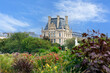 Colourful flowers and plants in the Tuileries Garden, view of Louvre building. Paris, France. 