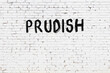 Inscription prudish painted on white brick wall