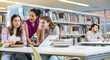 © JackF - Tree positive young adult women learning at library together, working with laptop and books and smiling