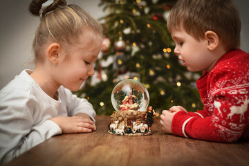 Children looking at a glass ball with a scene of the birth of Jesus Christ