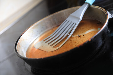 Frying pan with spatula and used cooking oil on stove, closeup