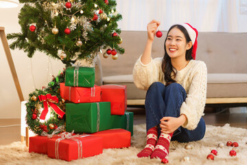 Christmas celebration concept, Young asian woman holding red ball to decorating in christmas tree