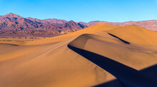 Sunset At Sand Dunes - Spring Sunset View Of Smooth And Curvy Sand Dunes Towering At Front Of Rugged Purple Mountains Of Amargosa Range. Mesquite Flat Sand Dunes Of Death Valley National Park, CA, USA