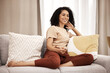 © Rene L/peopleimages.com - Happy, woman and watching tv on a sofa, relax and laughing at comedy, movie and film in her home. Television, black woman and streaming show, entertainment and humour on a couch in a living room