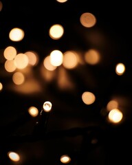 Vertical shot of Christmas lights in bokeh on a black background