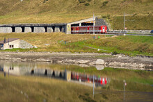 Beautiful Landscape At Oberalppass With Lake And Reflections Of MGB Train And Mountain Panorama On A Sunny Late Summer Day. Photo Taken September 5th, 2022, Oberalp Pass, Switzerland.