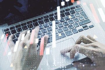 Multi exposure of abstract financial graph with world map and with hand typing on laptop on background, financial and trading concept