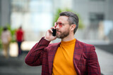 Fototapeta Miasto - handsome man in glasses speak on phone. man speak on phone outdoor. phone communication.