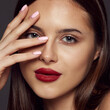© Lustre Art Group  - Close-up portrait of young beautiful brunette girl with red lips isolated over dark grey background. Beauty poducts. Concept of beauty, fashion and cosmetology