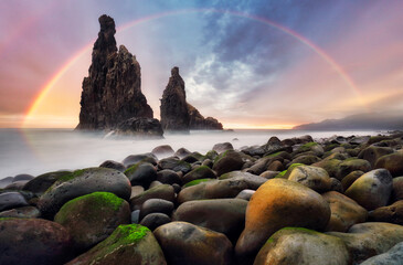 Wall Mural - Rainbow sunrise rocky coast with monumental rocky cliff and blurred sea water. Madeira island, Portugal