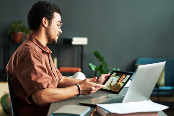Poster - Young confident man looking at teacher making presentation on tablet screen and discussing points of new subject during online lesson