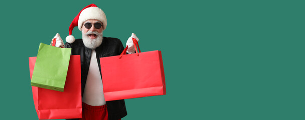 Wall Mural - Cool Santa Claus in leather jacket holding shopping bags on green background with space for text