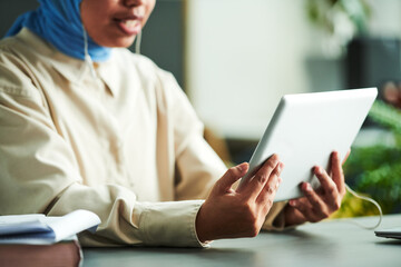 Poster - Hands of young Muslim tutor holding tablet in front of herself while communicating with online student or audience during online lesson