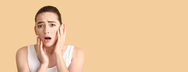 Worried young woman with acne problem on beige background with space for text