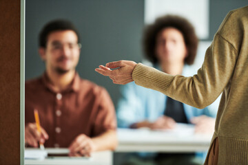Poster - Selective focus on hand of mature teacher or speaker making presentation of new subject in front of students at seminar