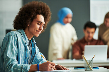 Poster - Side view of young multi-ethnic student looking at paper with grammar test and pointing at it while thinking of right answer at lesson